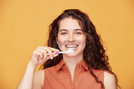 带着健康笑容的年轻大笑褐色女人每天早上刷牙独自站在镜头前图片
