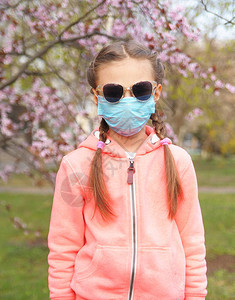 穿着保护药面罩的可爱女孩长着开花樱桃的枝子检疫科图片
