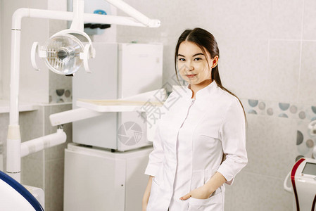 开朗的女牙医在她的办公室里微笑牙科学生站图片