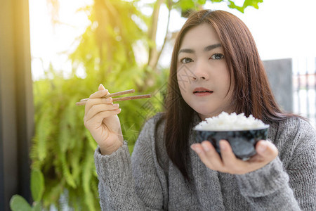 手持茉莉花大米碗的亚洲妇女拿着筷子图片