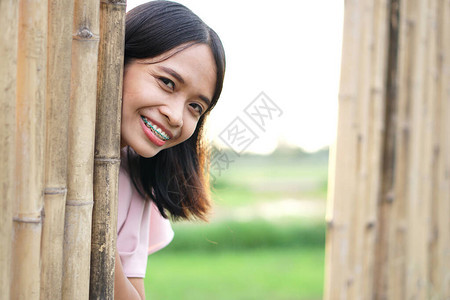 亚洲女人从竹墙上探出脸惊喜背景图片