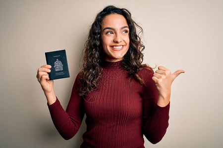 度假时留着卷发的年轻美女游客拿着加拿大加拿大护照指着图片