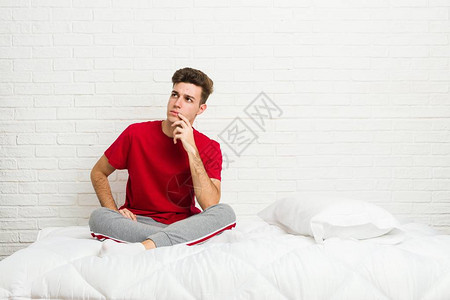 床上的年轻少年学生男人一边看侧面怀疑图片