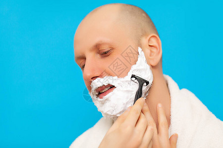 浴室里的男人用剃须刀刮胡子图片
