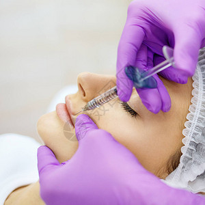 在美容诊所接受复健手术的漂亮女孩注射填充剂穿紫色手套的医生图片