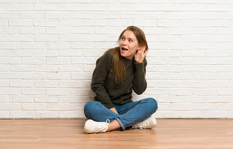 坐在地上的年轻女士坐在地板上听着一些东西图片