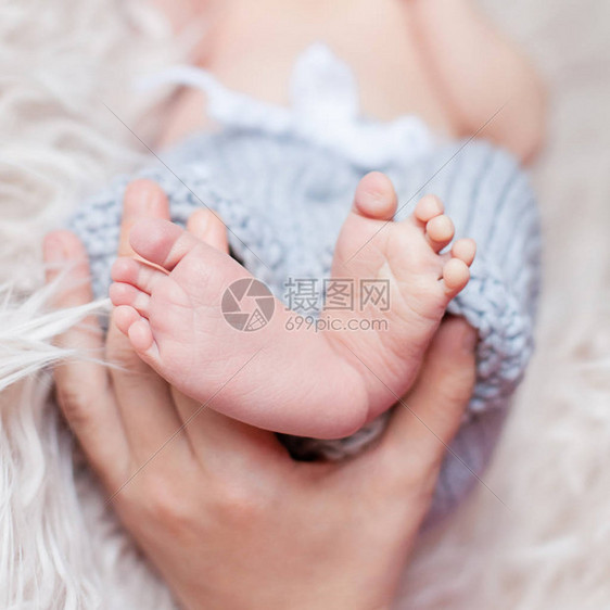 父母亲握在新生儿小脚的手里紧图片