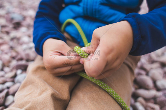 一个孩子学习用绳子打结一个小男孩正试图打结童子军训练儿童图片