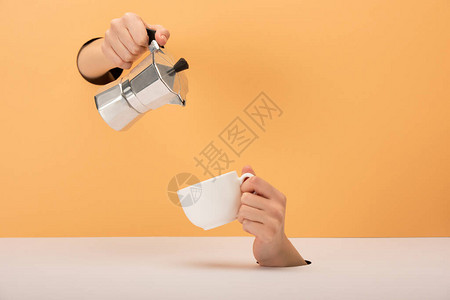 妇女将咖啡壶放在橙色和白色杯子旁边的妇图片