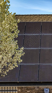 垂直高框架太阳能电池板位于房屋的深色倾斜屋顶上图片