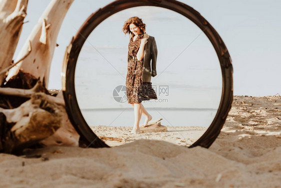 在阳光明媚的沙滩上穿着衣服拿着夹克手牵走在镜子的反射中图片