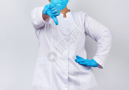 身穿白大褂和面罩手上戴着蓝色医用乳胶手套的女医生图片