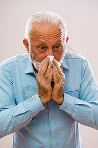 老人过敏和擤鼻涕的肖像图片