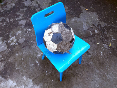 一个凌乱的足球躺在街上院子里的一个小儿童椅上图片