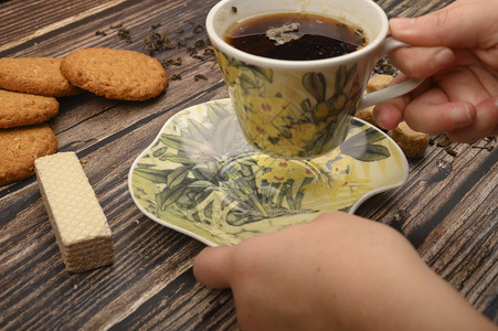 女孩的手拿着一杯黑茶燕麦饼干华夫饼茶叶木图片