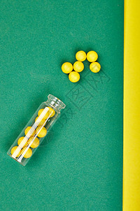 医学博客的极简主义风格模板小玻璃瓶小黄色和绿色药丸溢出纸背景制药概念图片