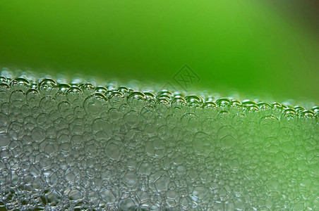 苏打水,上面绿色石灰色光线照亮的水中任何泡沫肥皂泡的背景