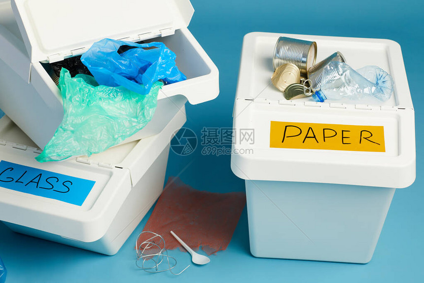 蓝色背景下塑料和废纸全垃圾箱的特写分图片