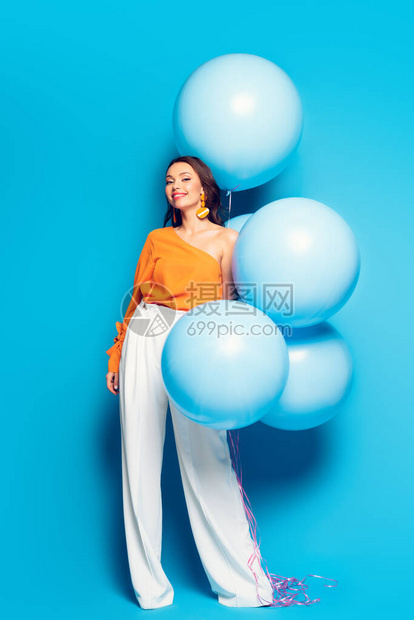 满的景象是快乐的时髦女人带着盛大的喜悦气球在蓝色背景图片