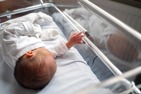 一个刚出生的婴儿躺在医院的一个盒子里小宝向摄影师展示了他的手玻璃后图片