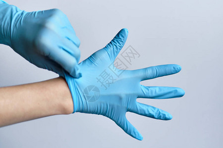 把蓝色医疗手套贴在白色背景的手上的过程图片