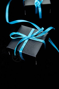 有蓝色丝带的豪华黑色礼物盒在闪耀的黑色背景图片