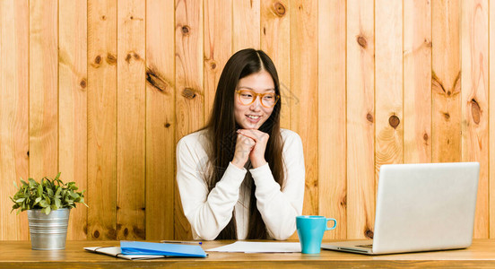 在桌子上学习的年轻女人把手放在下巴面看图片