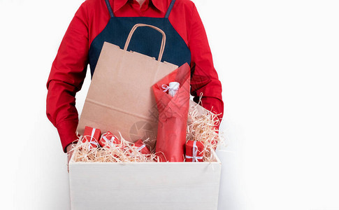 红衬衣和围裙手持礼品包装盒和白底酒瓶图片