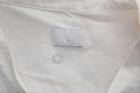 棉衬衫背景上的白色空白服装标签图片