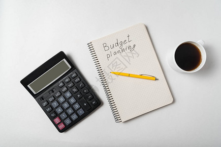 预算规划文本的小册子计算器笔记本和白底咖啡杯图片