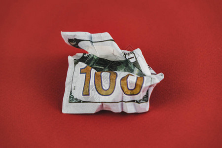 躺在红色背景上的皱巴的百元钞票图片