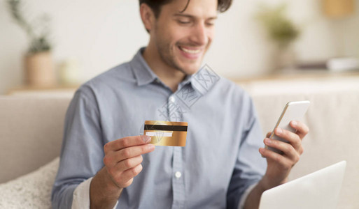 网上购物持信用卡和智能手机的人坐在图片