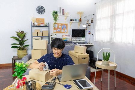 制作包裹装纸板盒供交付过程的青年企业家图片