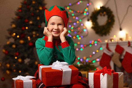 穿小精灵服装的小男孩和圣诞礼物在图片