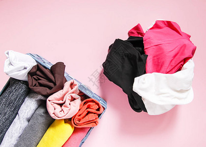 家用衣柜内垂直储存的多彩衣服软粉红色背景的纺织品盒图片