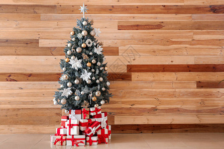 装饰圣诞树和木墙附近的礼物图片