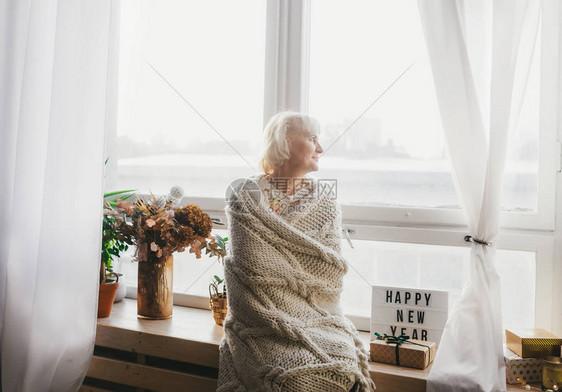 高龄妇女向窗边看望和享受圣图片