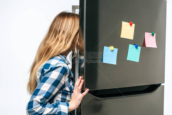 女人看着开的冰箱上面贴着粘黏纸条的女人图片