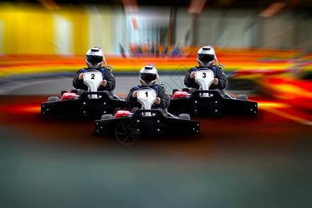 三名车手去卡丁车速度在赛道的背景上进行室内比赛背景图片