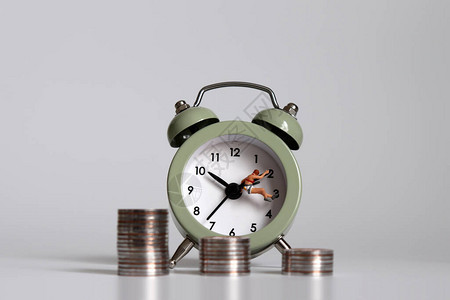 一个有闹钟和一堆硬币的微型人工作时间和收入图片