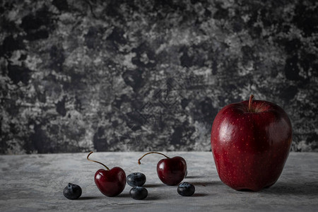在古老灰色桌子上配有樱桃和蓝莓的苹果背景图片