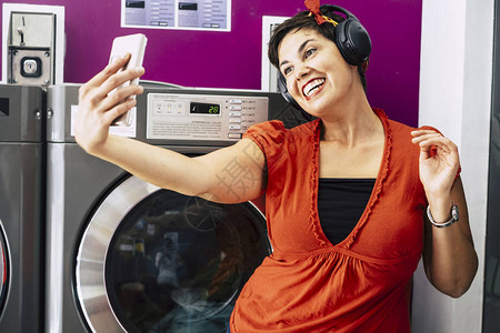 黑发美女在洗衣店用智能手机自拍图片