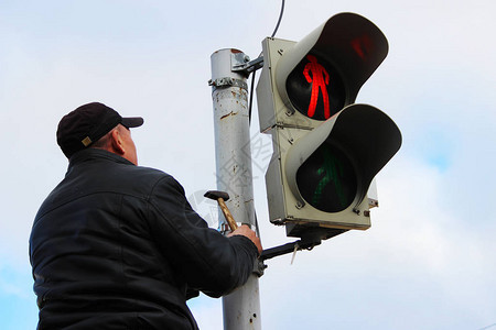 工人在交通灯柱上为路标行人跨过路牌准备图片