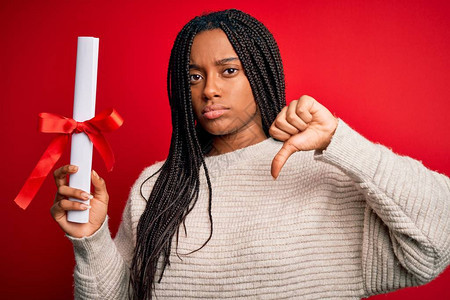 年轻的非洲裔美国女学生在红色孤立的背景下持有大学文凭图片