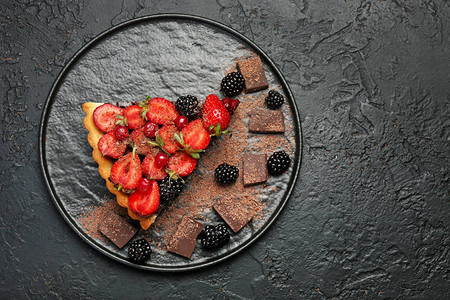 黑底带一块美味巧克力草莓蛋糕的盘子放图片
