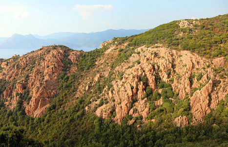 法国科西卡岛丘陵的荒瘠地貌以及夏季红石和深海背景的红石图片