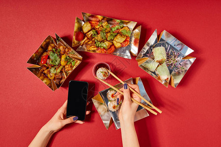 女人用蒸炸包和智能手机拿着筷子图片