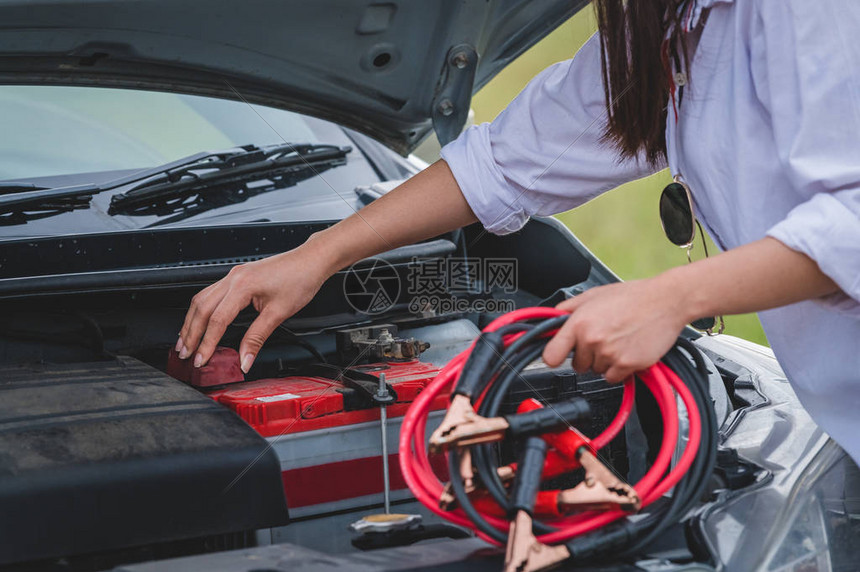 女手持电池缆铜线自行将电池与红黑线连接至电端子修复破损汽车的特写汽车维图片