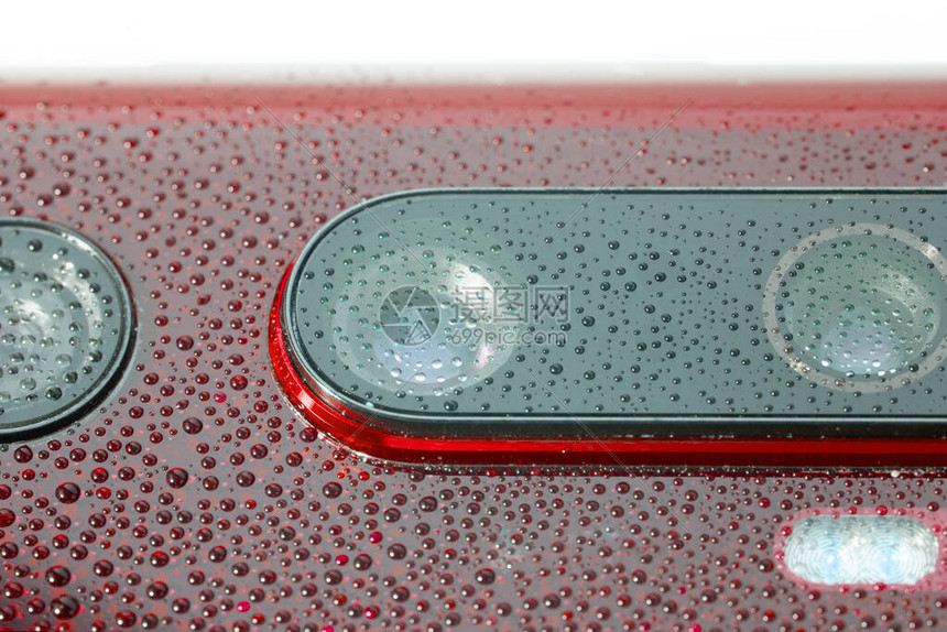 红色手机摄像头镜覆盖着小水滴有选择地聚焦图片