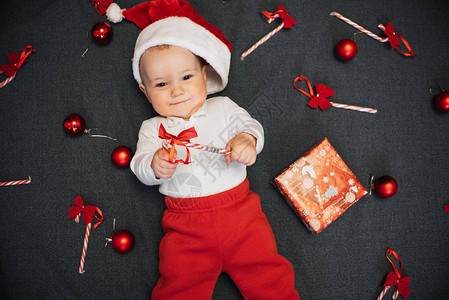 帽子中快乐的婴儿男孩在圣诞糖果甘蔗红球和图片